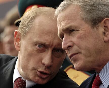 Russian President Vladimir Putin talks with President George W. Bush during a parade at Red...