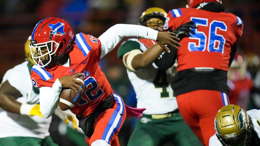 Duncanville quarterback Keelon Russell (12) scrambles away from the DeSoto pass rush during...