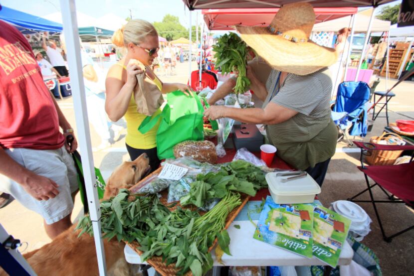Loraine Jarocki, left, of Dallas purchases greens from a vendor at the White Rock Local...