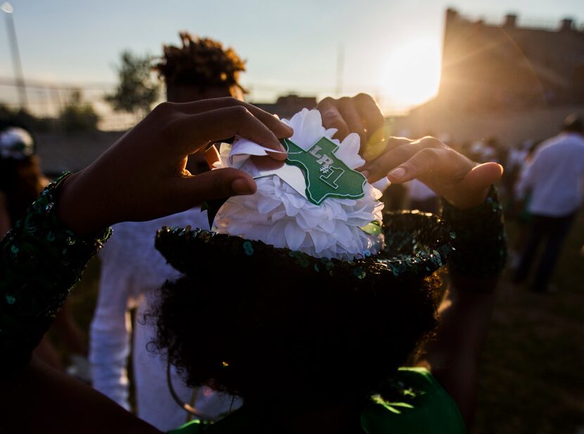 Mansfield Lake Ridge dance team members pin homecoming mums to their hats as they warm up...