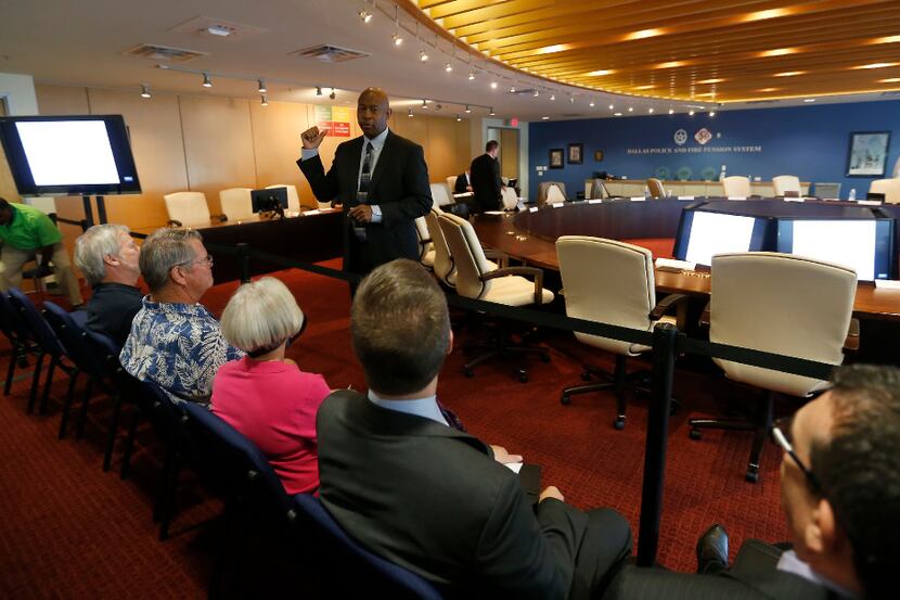 Chairman Sam Friar (standing in a suit) talks with people in the audience during a break at...
