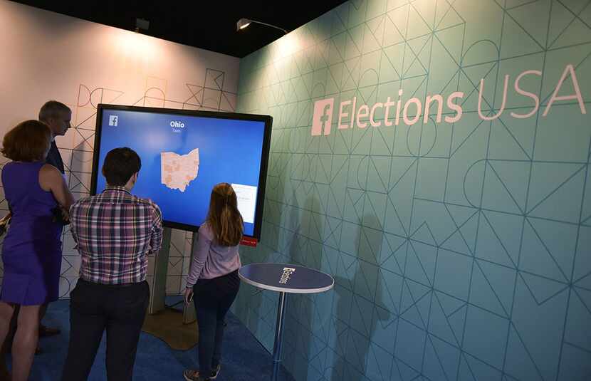  People gather in front of a monitor at the Facebook lounge at the Quicken Loans Arena ahead...