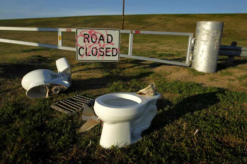 A pair of abandoned toilets lie next to a levee gate the West Levee of the Trinity River on...