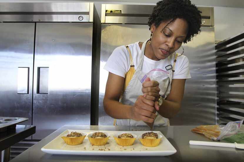 Juakita Berkley ices the mini-cheesecakes for her small business "Top That Cheesecake" in...