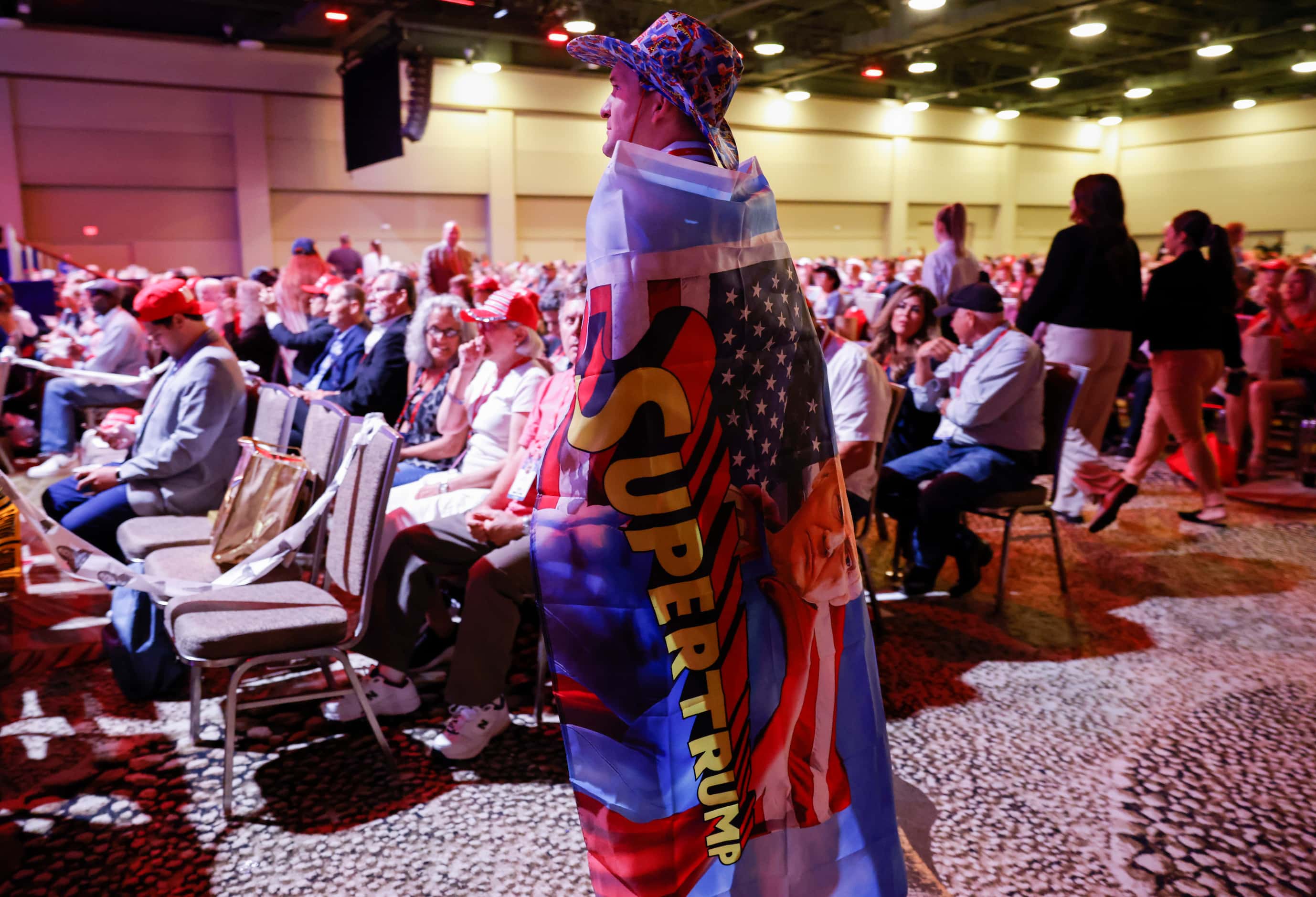 An attendee wearing cape reading “Super Trump” watches the third day of Conservative...