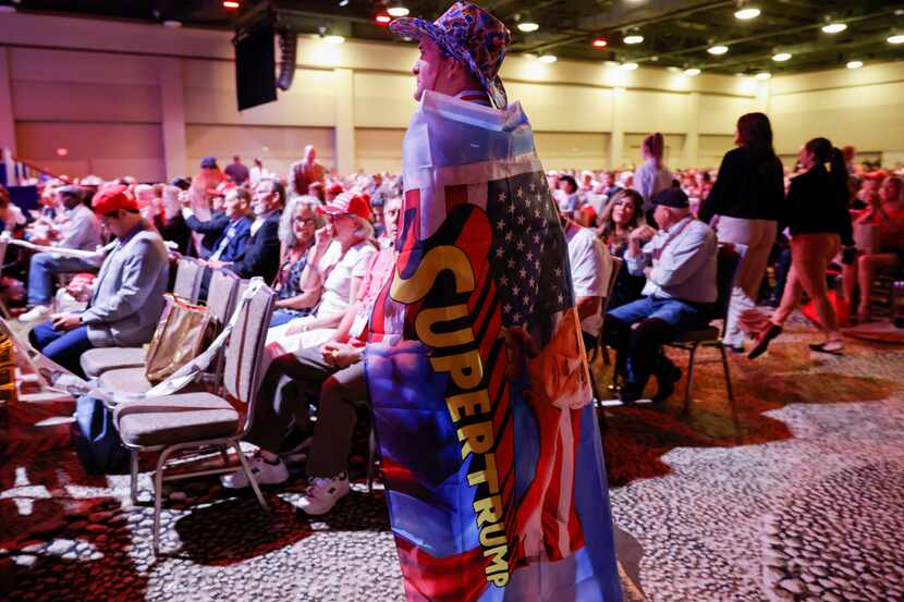 An attendee wearing cape reading “Super Trump” watches the third day of Conservative...