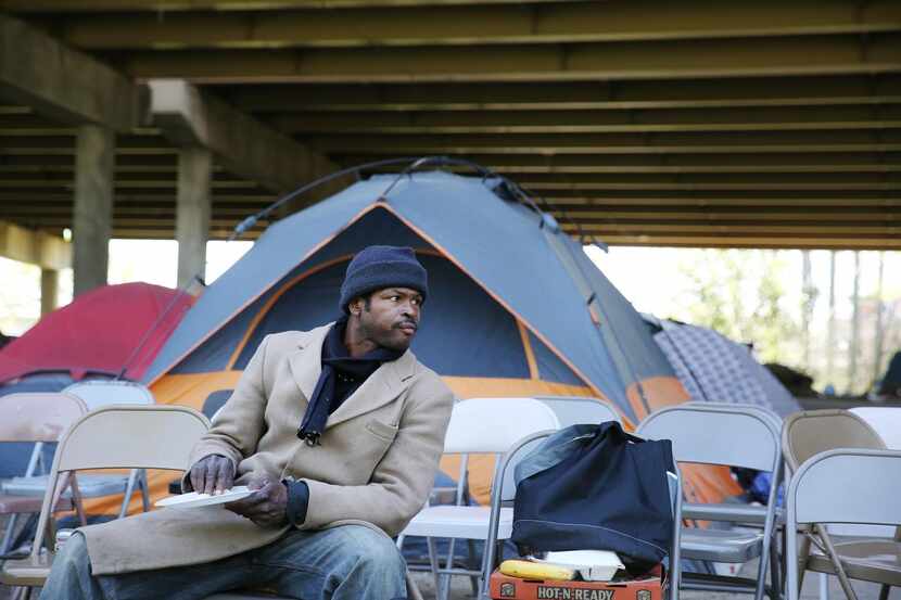 
Jerome Miller, who is homeless, but does not live in Tent City, sits while eating food...