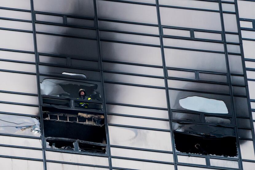A firefighter looks out from the window of a damaged apartment in Trump Tower in New York on...