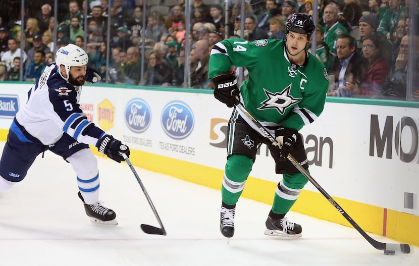 DALLAS, TX - JANUARY 15: Jamie Benn #14 of the Dallas Stars skates the puck against Mark...