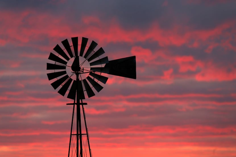 The sun sets behind a windmill along Old San Antonio Road in Brazos County on Jan. 10.