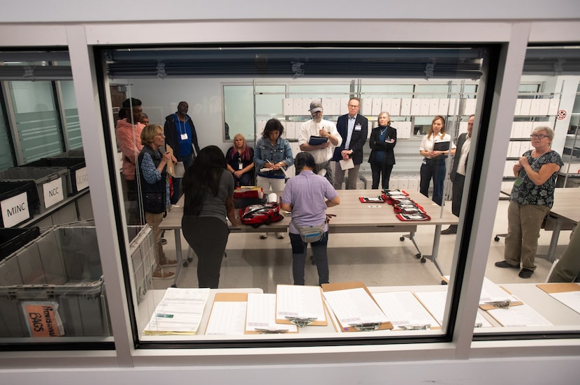 Poll watchers and election officials organize election materials from voting sites at the...