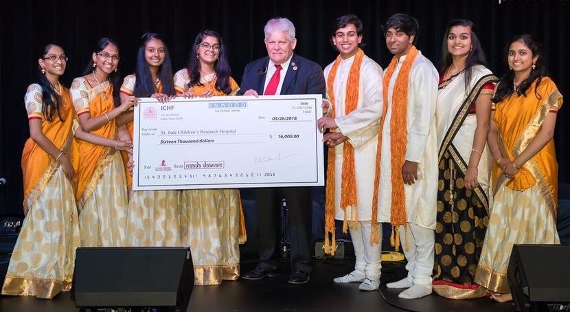 Eight organizers of a carnatic music benefit concert present a $16,000 check to Allen Mayor...