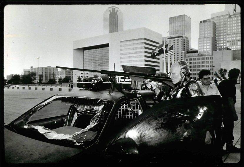 The Dallas skyline looms behind actor Peter Weller during filming of the 1987 dystopian film...