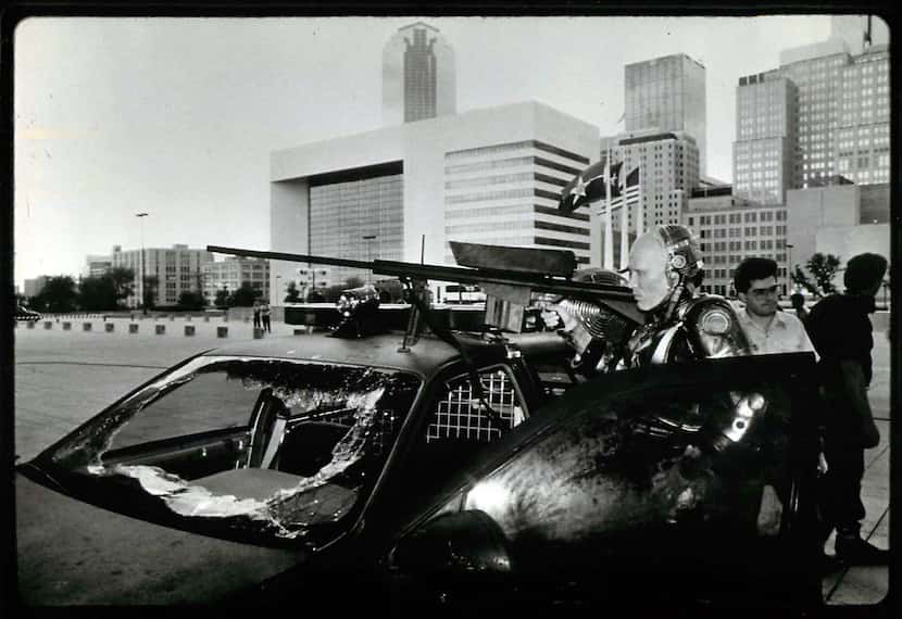 The Dallas skyline looms behind actor Peter Weller during filming of the 1987 dystopian film...