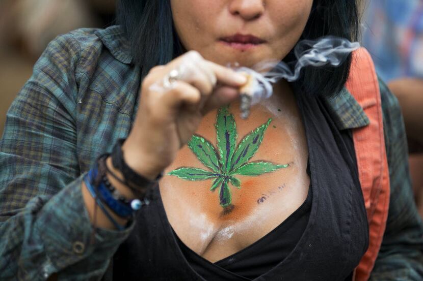 FILE - In this May 3, 2014, file photo, a young woman smokes a joint during a rally calling...