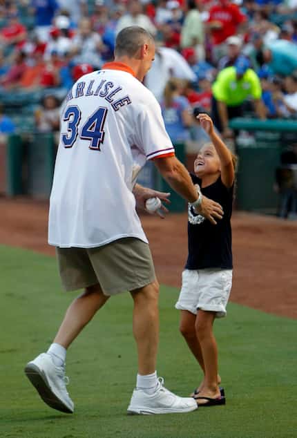 Dallas Mavericks head coach Rick Carlisle hugs his daughter after throwing the first pitch...