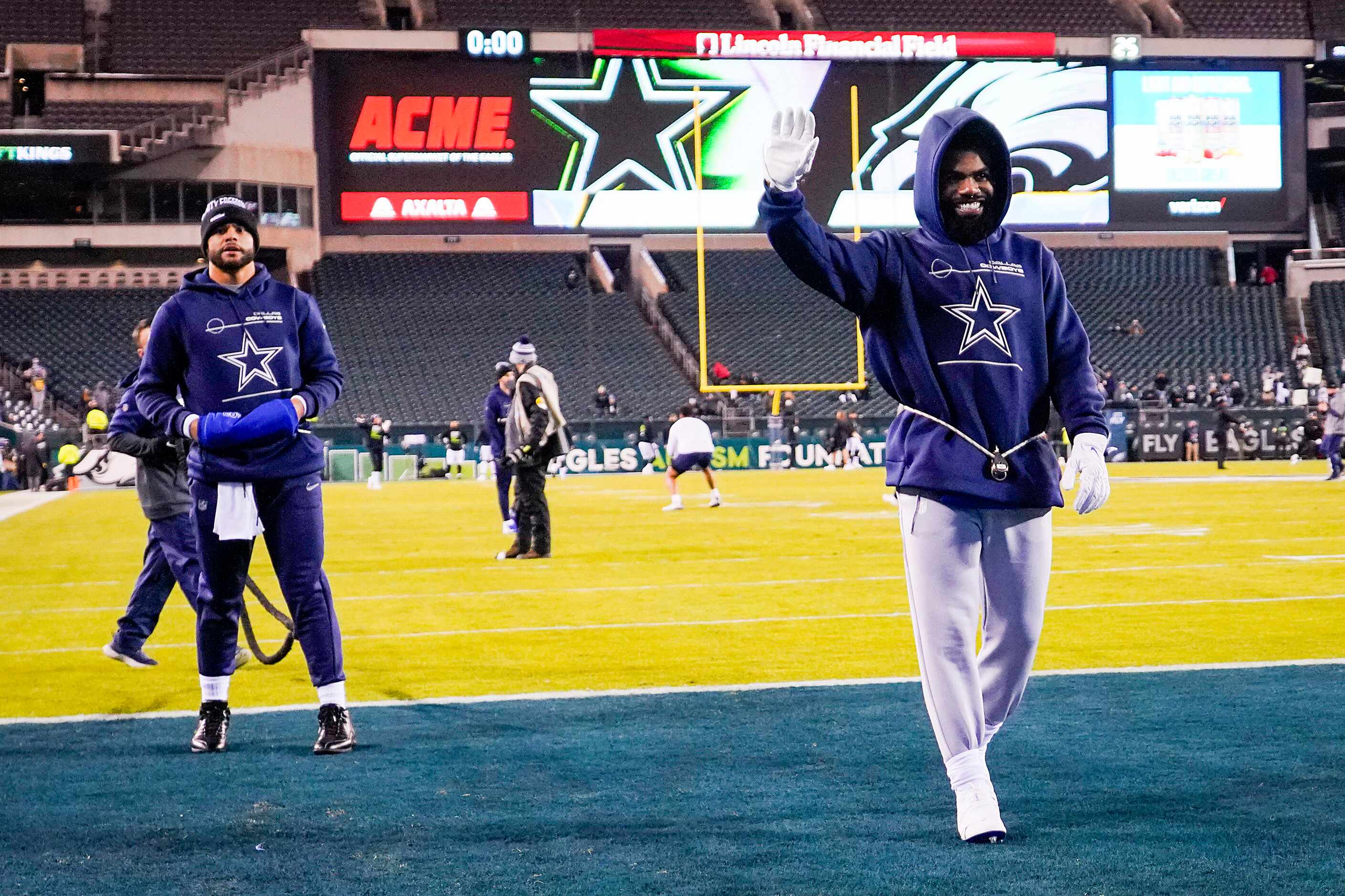 Dallas Cowboys running back Ezekiel Elliott waves to fans as he warms up with quarterback...