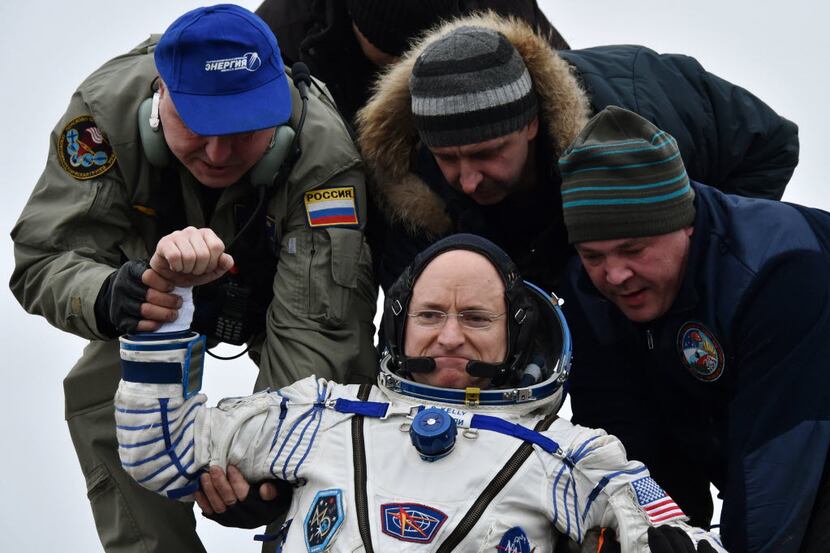 Ground personnel help astronaut Scott Kelly get out of a Soyuz space capsule after landing...
