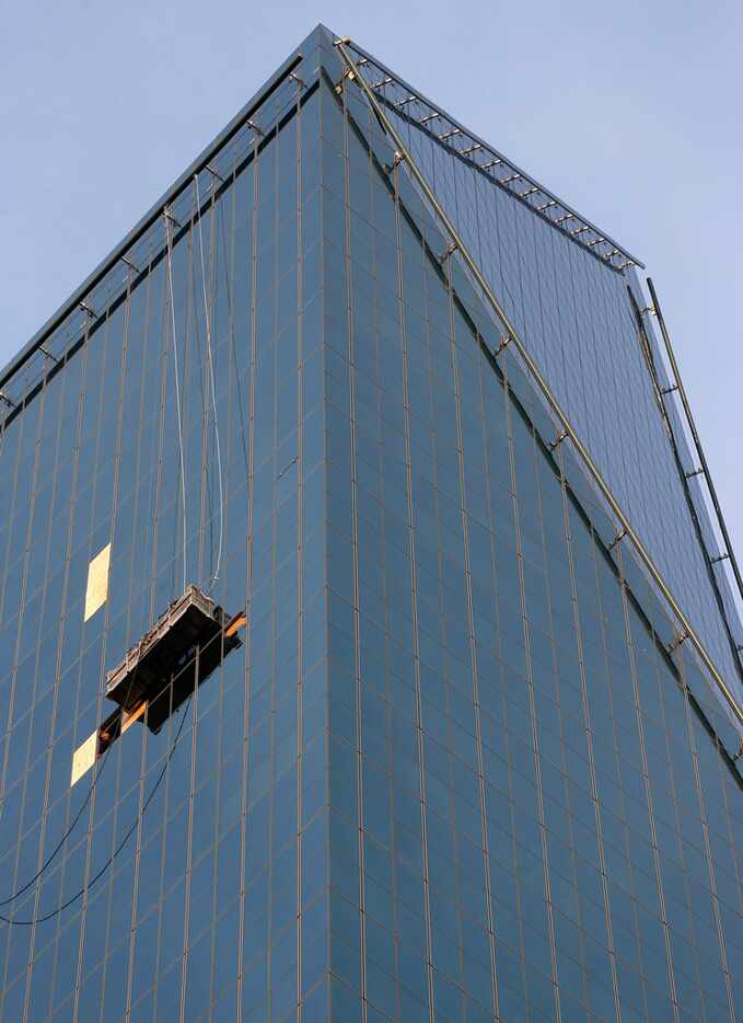 Workers repair broken windows on floors about 30 stories up at Fountain Place in downtown...