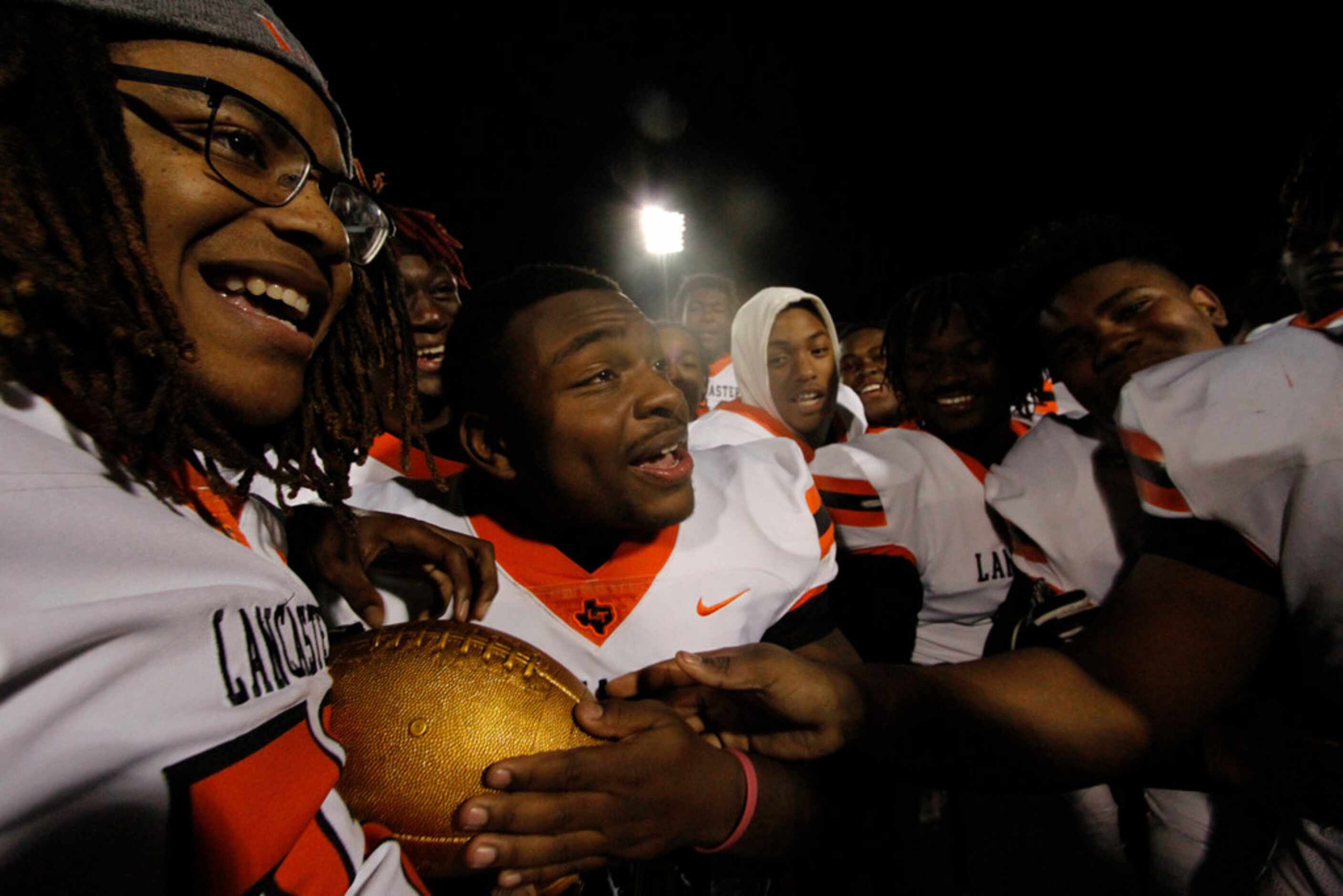 Members of the Lancaster Tigers move in to touch the Division l area trophy held by Kalen...