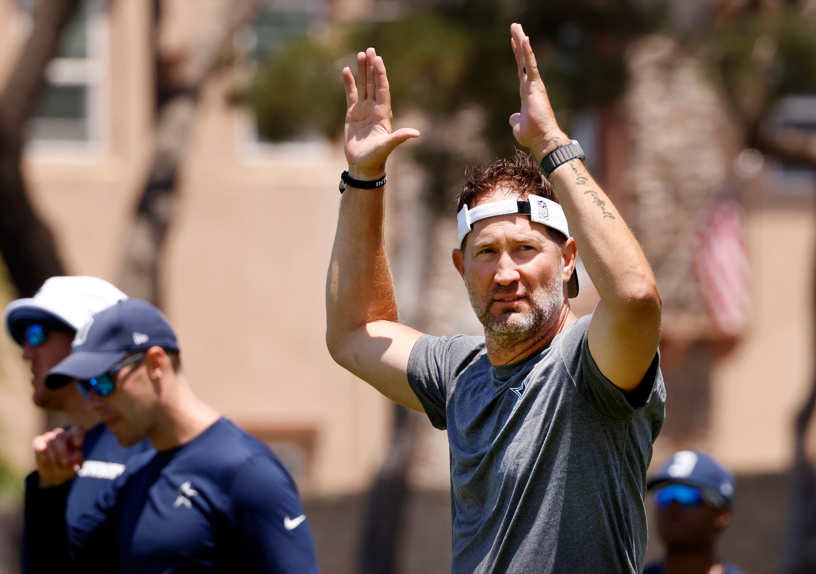 Dallas Cowboys offensive coordinator Brian Schottenheimer  waves to his players as they run...