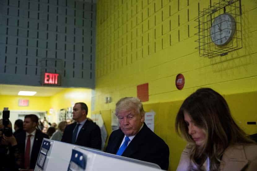 Donald Trump glances over at his wife, Melania, as she votes at a polling station inside...