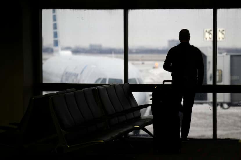 A traveler looks out a window at an American Airlines airplane at Terminal C on Wednesday,...