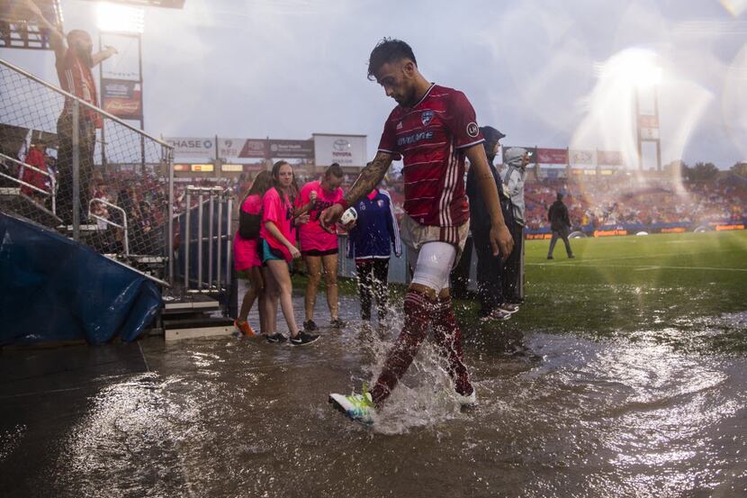 FC Dallas forward Maximiliano Urruti (37) splashes in rain water as he exits the field for a...