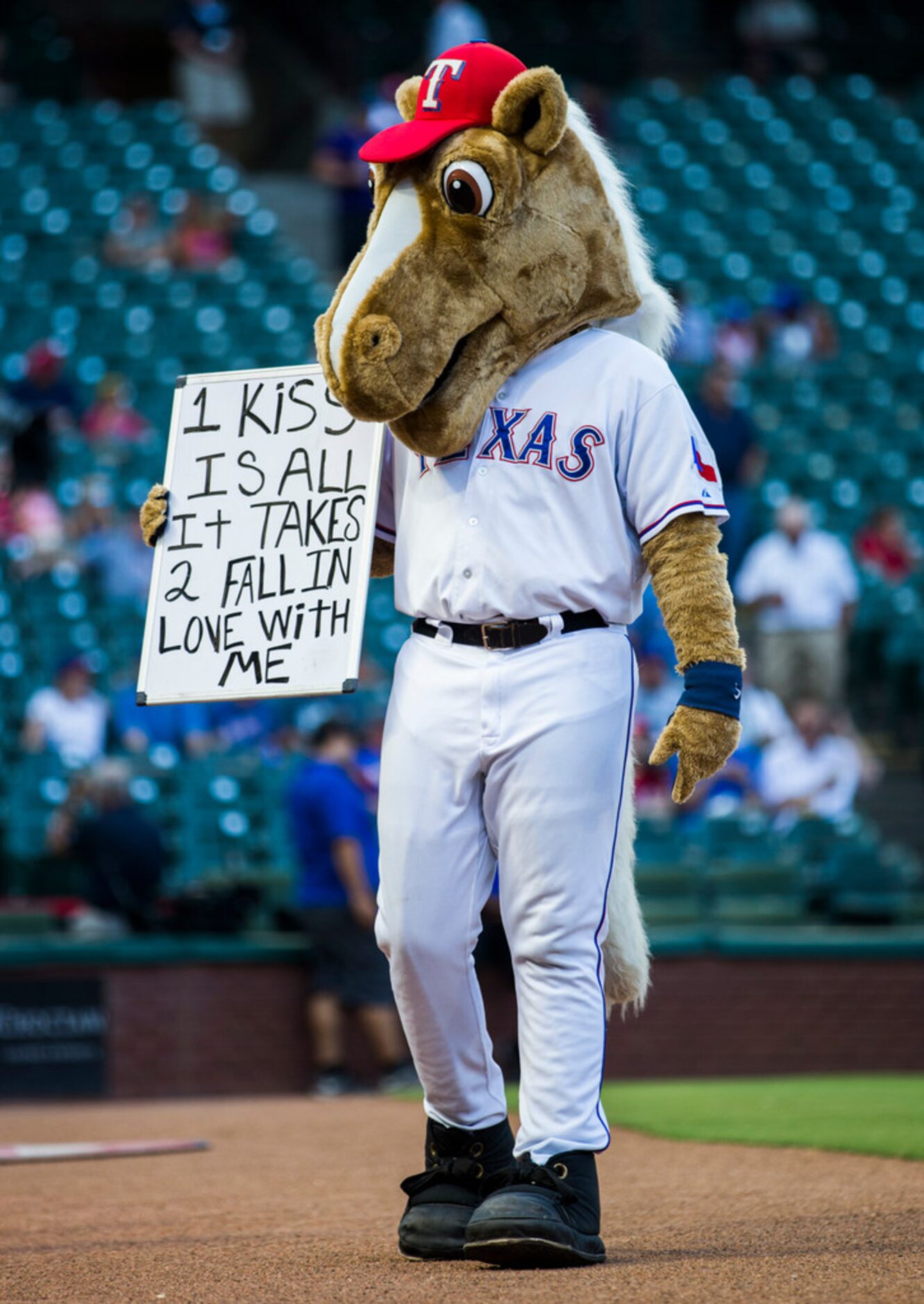 The Rangers mascot, Rangers Captain, walks around with a sign before an MLB game between the...