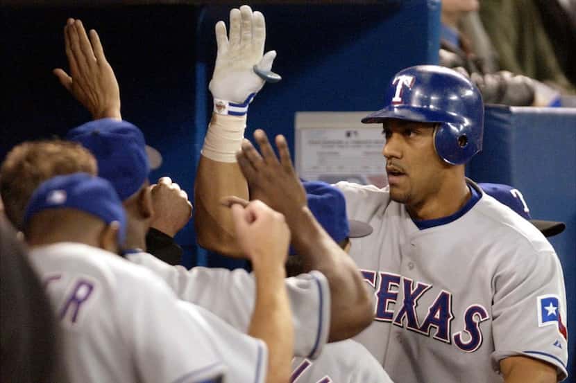 Texas Rangers' Juan Gonzalez, right, celebrates in the dugout after scoring on his two-run...