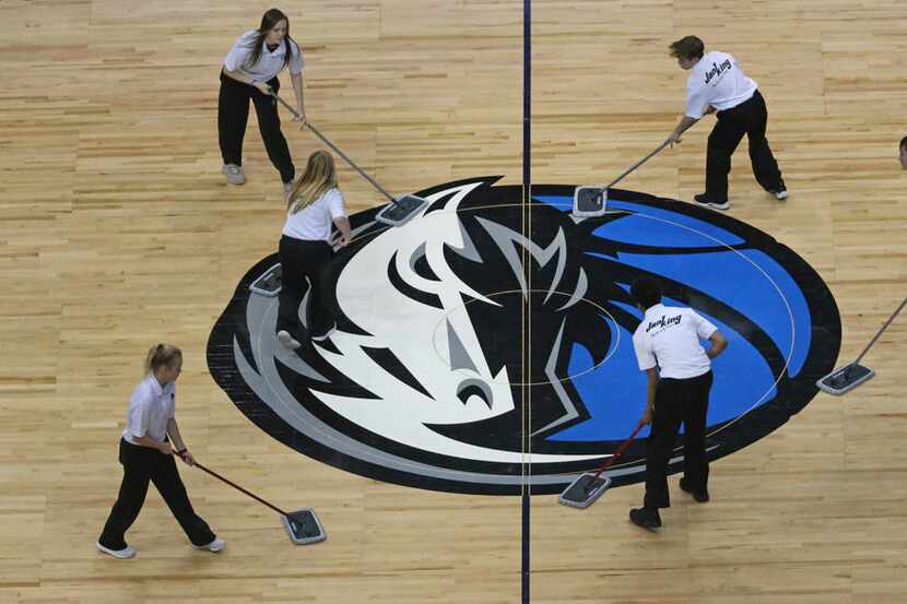 FILE - The Mavs logo at half court gets some TLC during a timeout in a game between the...