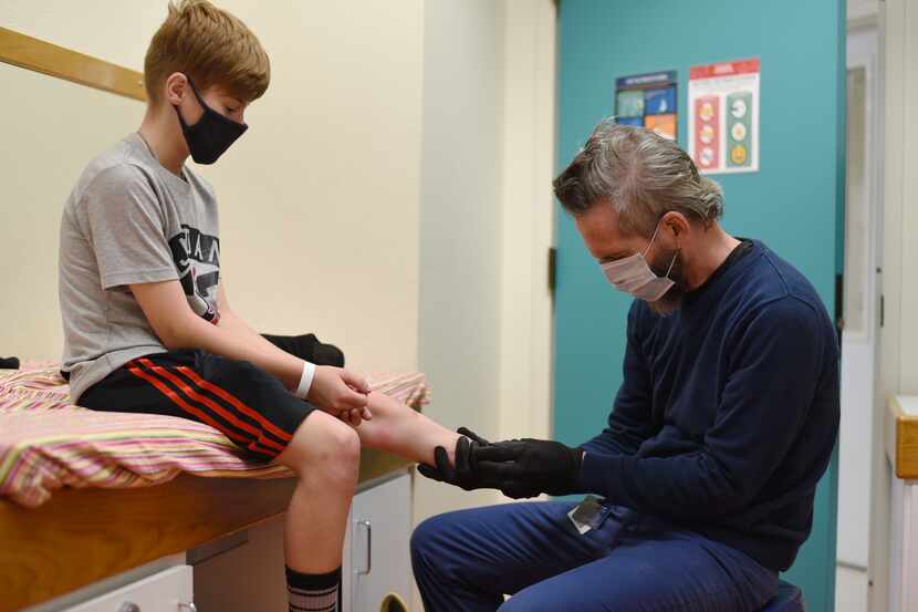 12-year-old Austin has his leg examined by prosthetics expert Dwight Putnam in an exam room...