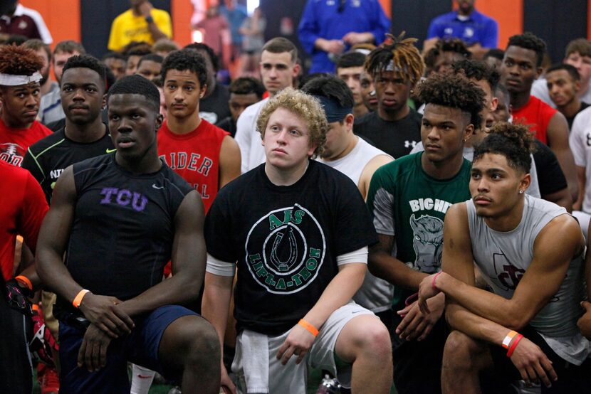 Arlington High School senior quarterback Caelen Day, center, listens to a football trainer...