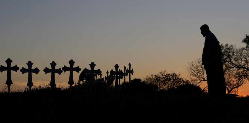 Isaac Hernandez and his wife Crystal visit a line of crosses before a vigil for the victims...