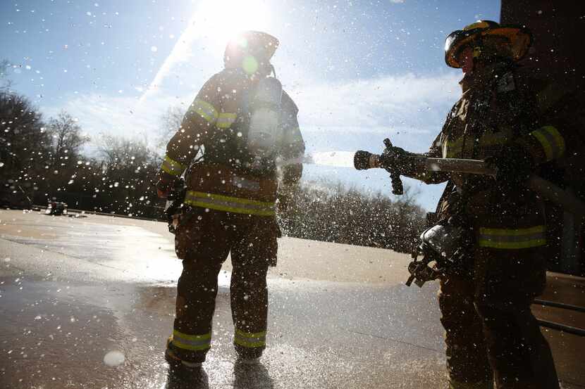 Dallas Fire-Rescue recruit Thomas Clark sprays recruit Ryder Bounds as part of a...