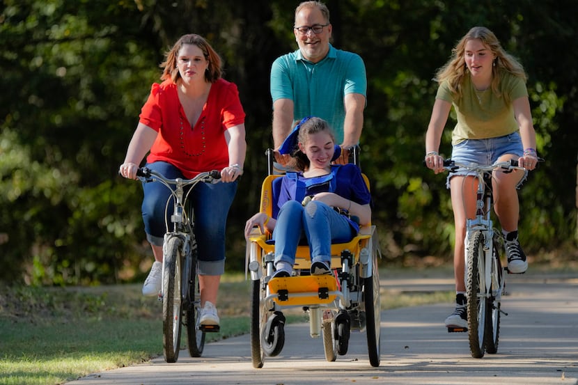 Shelby Sparks, 21, rides in a chair attached to the front of her dad's bicycle. Her father,...