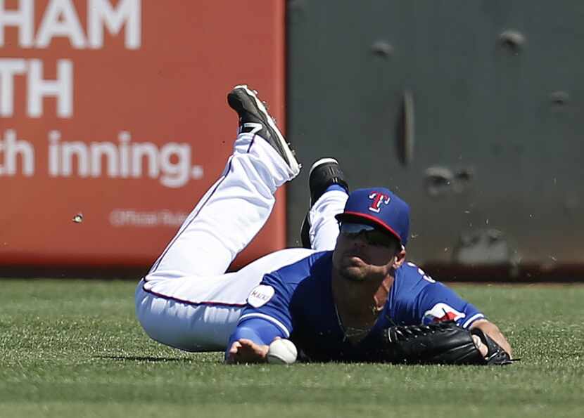 Mar 17, 2015; Surprise, AZ, USA; Texas Rangers left fielder Jake Smolinski (20) dives for a...