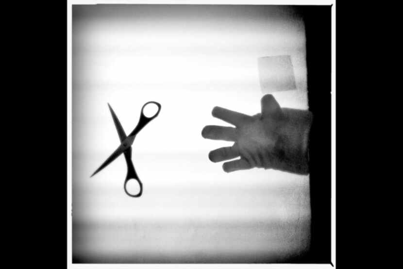 Scissors and a cotton glove sit on a light table.