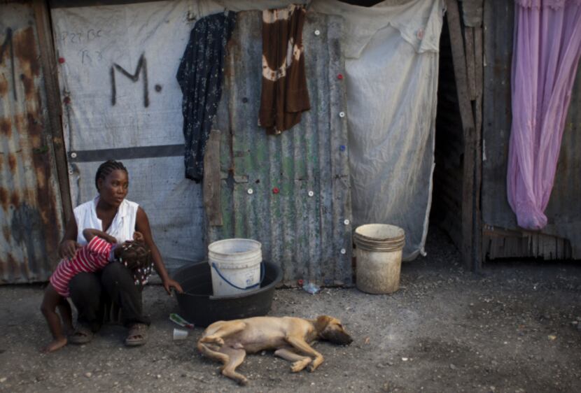 A woman sits with her daughter in front of her tent at a camp set up for people displaced by...