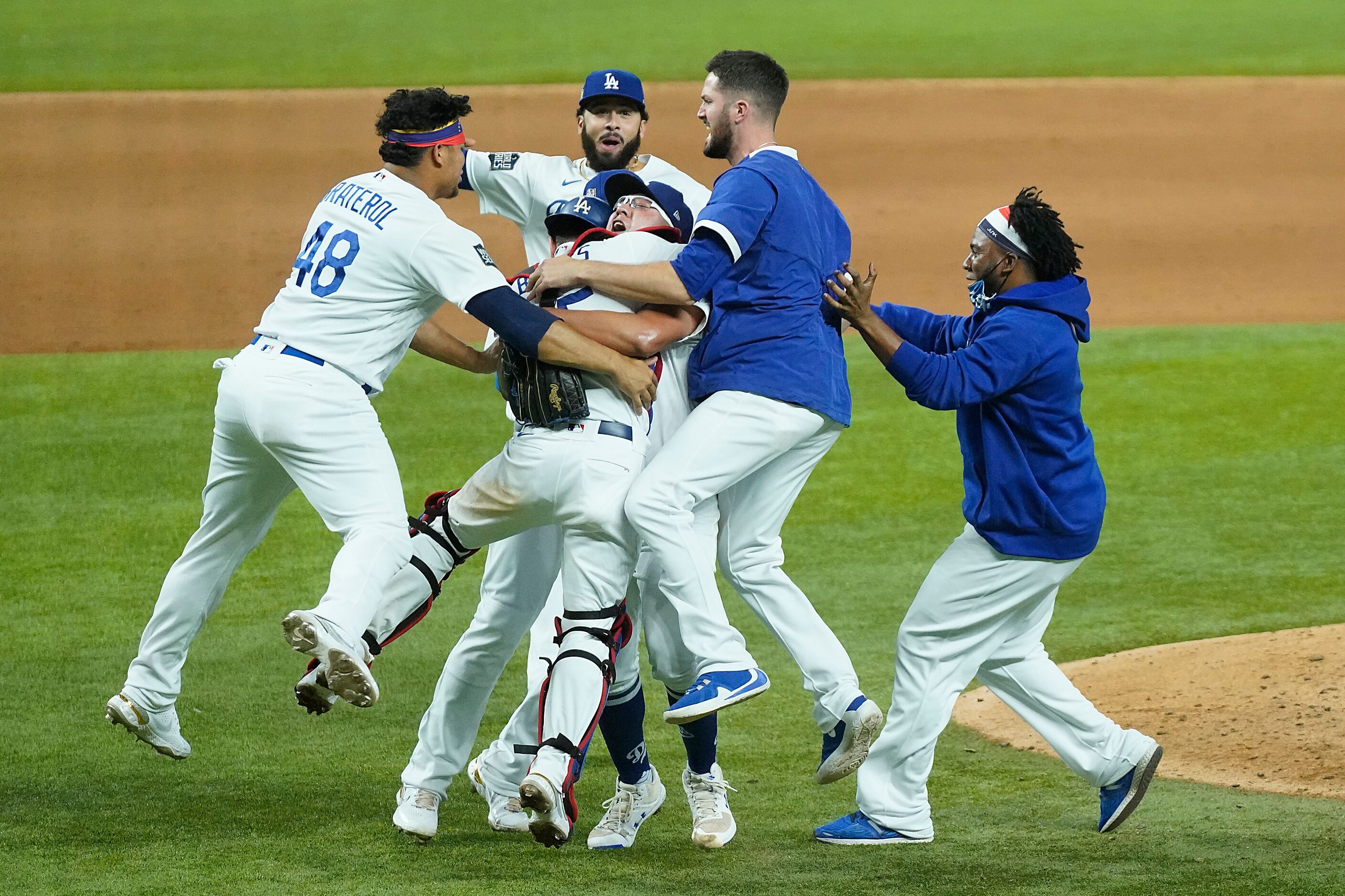 Los Angeles Dodgers players rush to join pitcher Julio Urias and catcher Austin Barnes as...