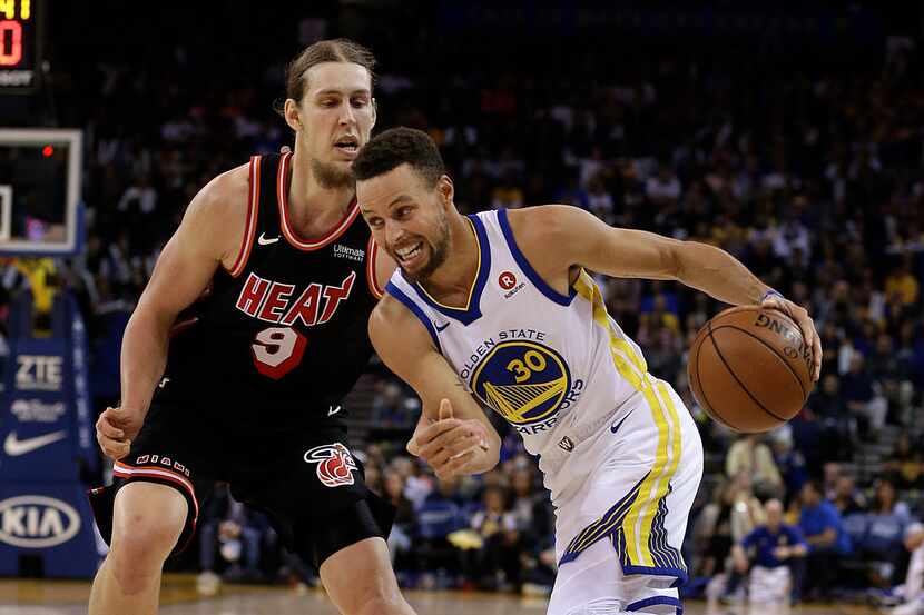 Golden State Warriors' Stephen Curry, right, drives the ball against Miami Heat forward...