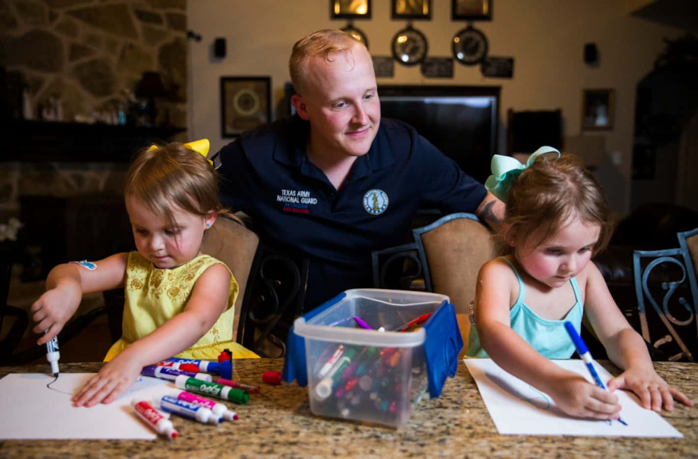 Josh Ragan watches as his daughters, Irie, 3,  and Aviana, 4, write letters to their younger...