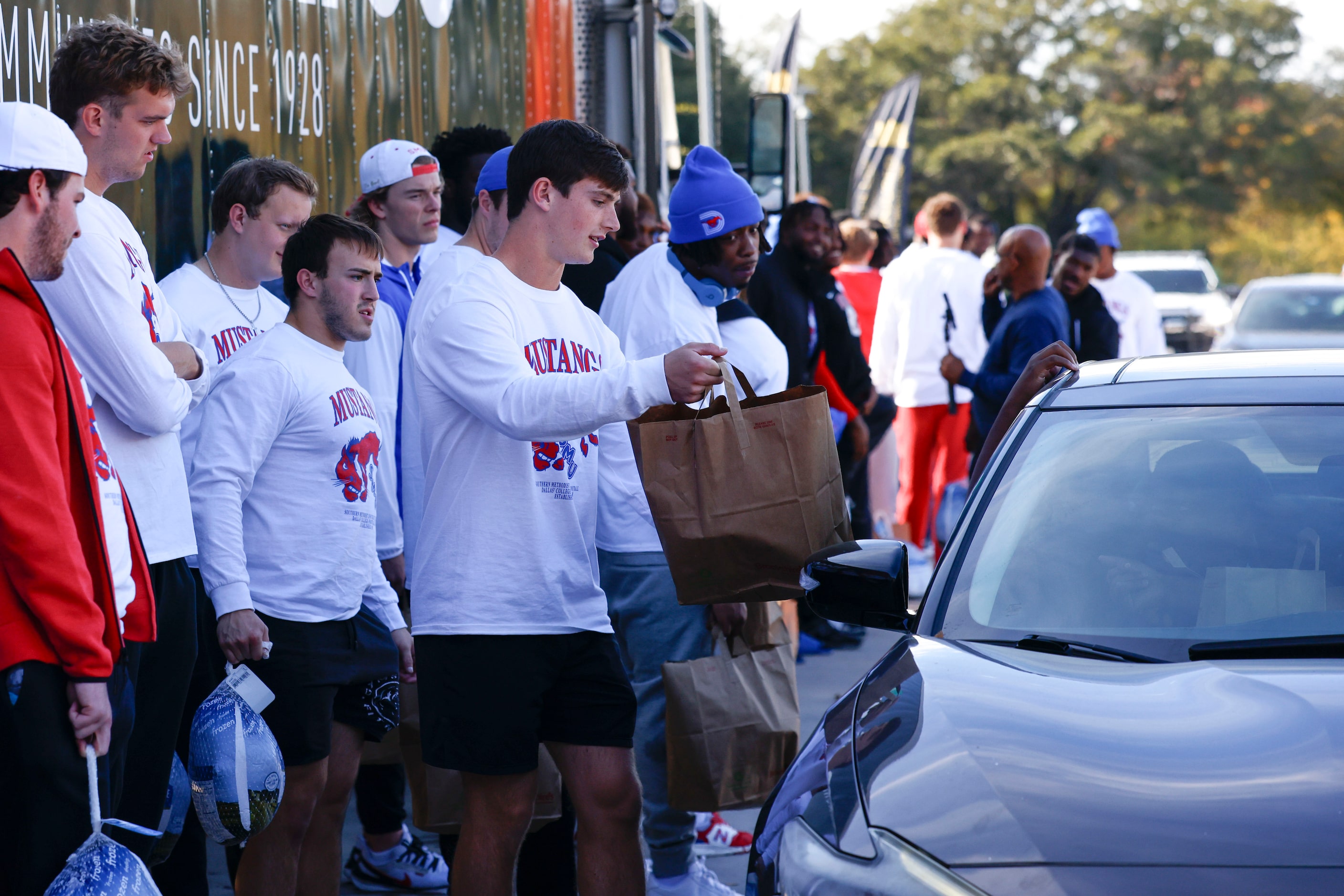 Southern Methodist University football players hand out free turkeys to incoming traffic, on...