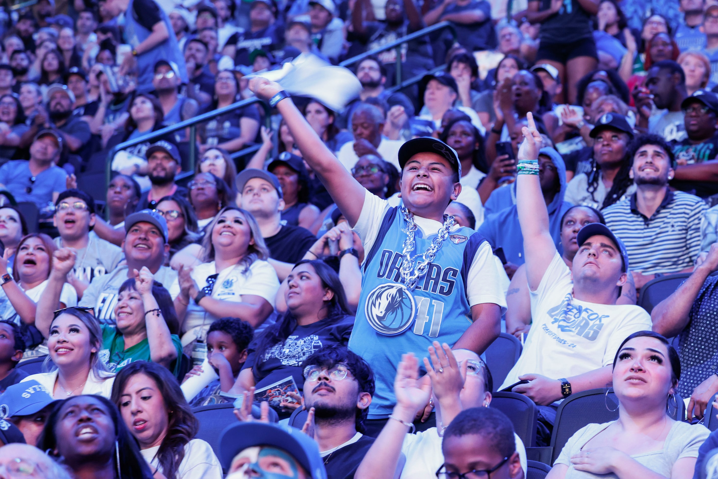 Damian Guerra, 10, (center), reacts as crowd cheer following a Dallas Mavericks point during...