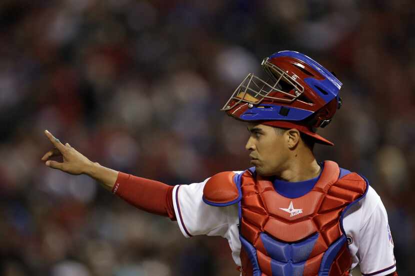 Texas Rangers' Robinson Chirinos signals to the team in the seventh inning of a baseball...