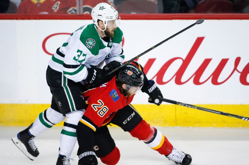 Dallas Stars' Justin Dowling, left, checks Calgary Flames' Elias Lindholm during the first...