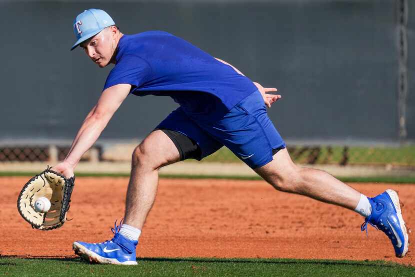 Texas Rangers infielder Justin Foscue takes grounders at first base during a spring training...