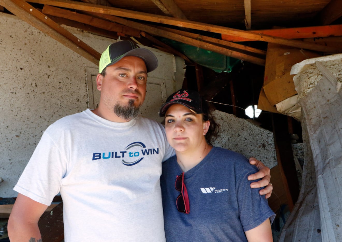 Bo and Britney Carroll stand inside of their collapsed garage in front of a green Christmas...