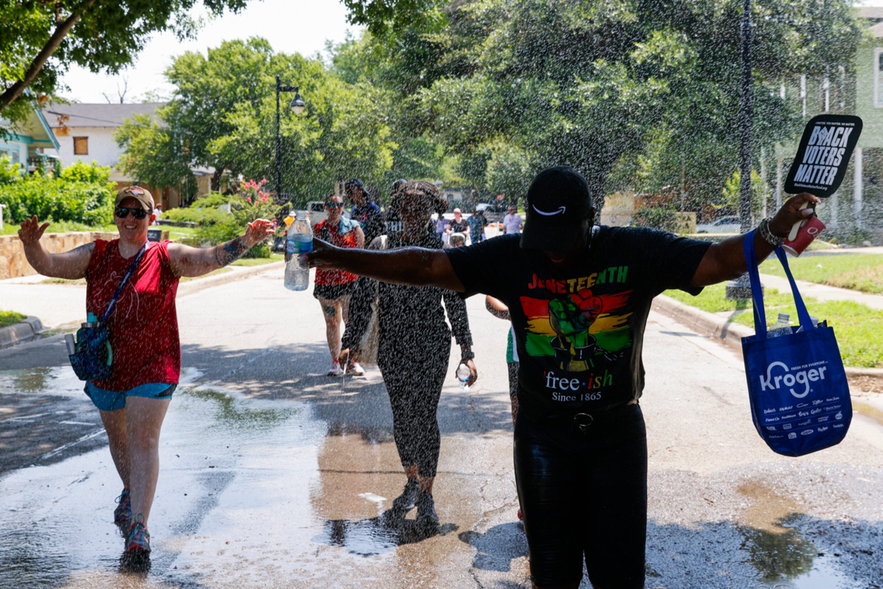 Crowd cools off as they walk by hose of water during Opal's Walk for Freedom on Monday, June...