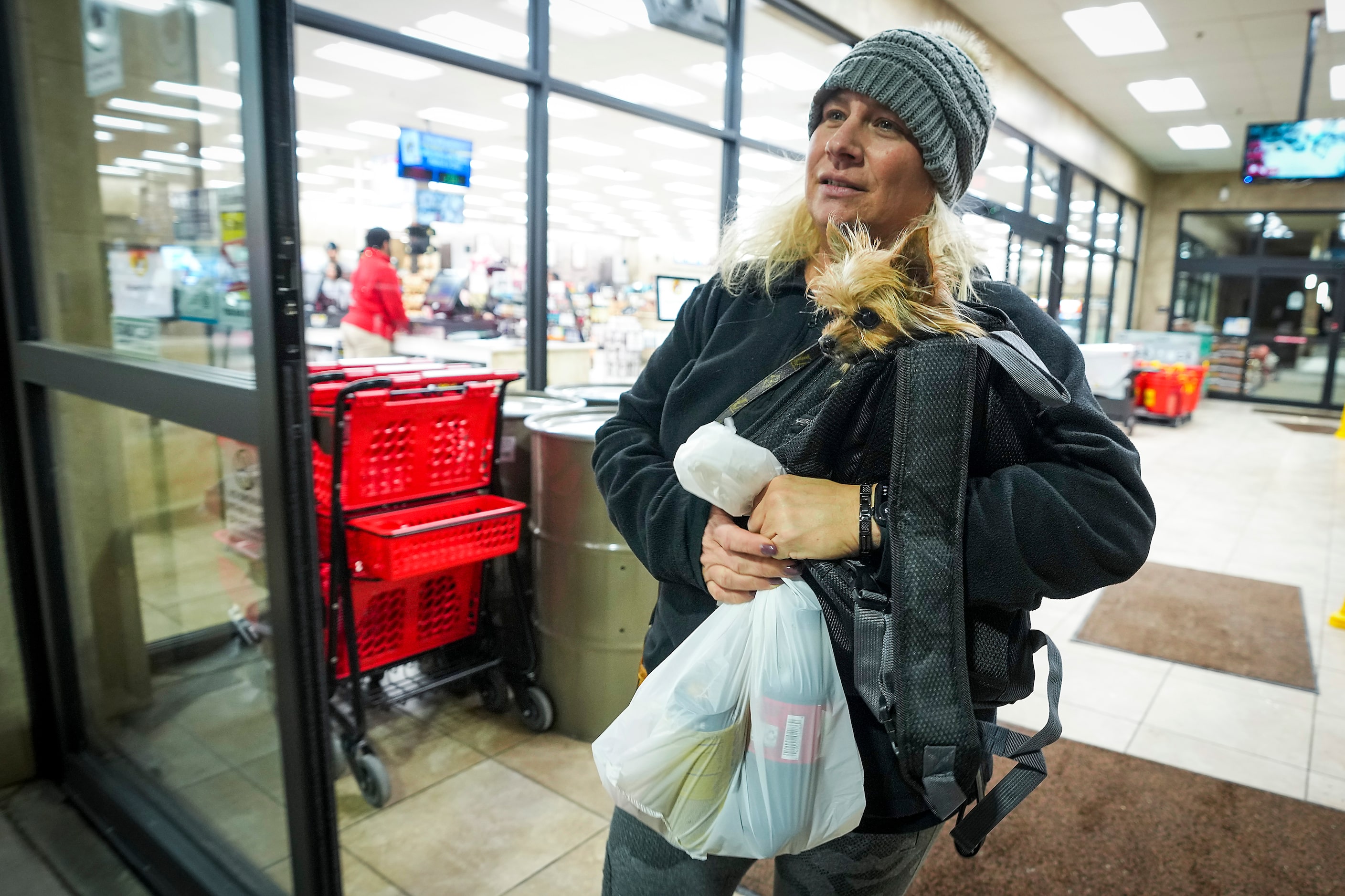 Rena Wilhelm carries her dog Benji as she prepares to check out after picking up snacks at...